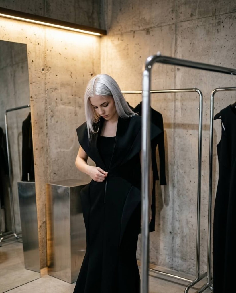 Lookbook in raw interior Platinum hair model in sculptural black piece, concrete showroom with racks and mirror